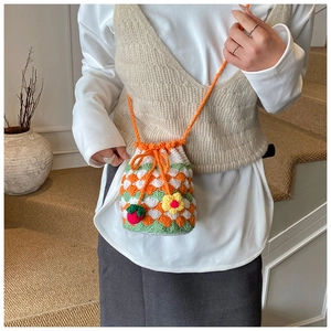 Detail of handmade crochet bucket bag with vibrant color-block pattern and cute charms