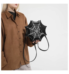 Detail of spider web shaped shoulder bag with white contrast stitching and spider accent