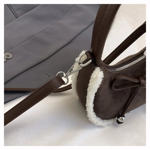 Detailansicht der braunen Wildledertasche mit weißem Pelzbesatz und Schleifendetail