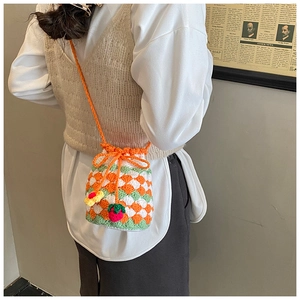Detail of crochet bucket bag featuring vibrant diamond patterns and cute strawberry charm