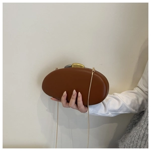 Detail of vintage brown acrylic clutch bag with artistic two-tone pebble metal clasp
