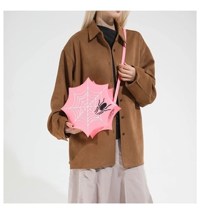 Pink spider web crossbody bag with black spider patch and embroidery on brown shirt