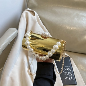 Détail macro d'un sac de soirée cylindrique doré de luxe avec poignée en perles et strass
