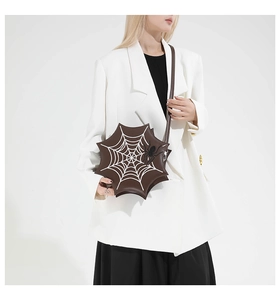 Macro detail of dark brown star-shaped bag with white spider web print and spider charm