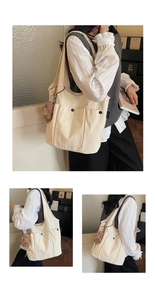 Detail of cream canvas tote bag featuring front snap pockets and a brown plush bear charm