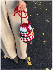 Detail of handmade crochet bucket bag with red drawstring and yellow sunflower charm