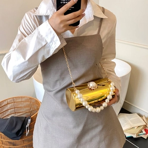 Détail de sac de soirée cylindrique doré avec poignée en perles et fermoir en diamant