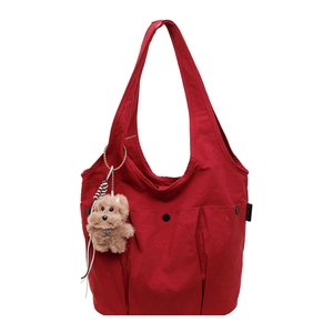 Detail of red canvas tote bag featuring three front pockets and a cute teddy bear charm