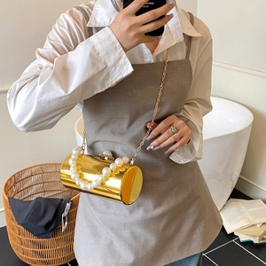 Pochette cylindrique dorée avec poignée en perles et chaîne portée par un modèle