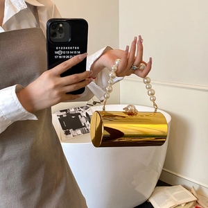 Détail du sac de soirée cylindrique doré avec anse en perles et finition miroir métal