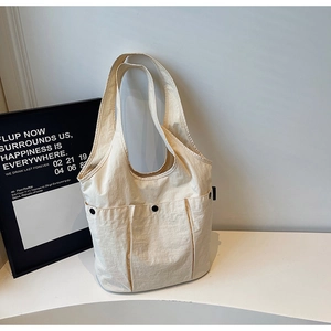 Detail of beige canvas tote bag showing three front pockets with black snap button closures