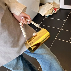 Détail du sac de soirée cylindrique doré avec poignée en perles et fermoir de luxe