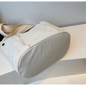 Detail view of large capacity white tote bag with wide shoulder strap and side button