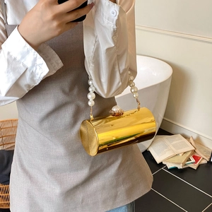 Détail du sac de soirée cylindrique doré avec anse en perles et fermoir métallique sûr