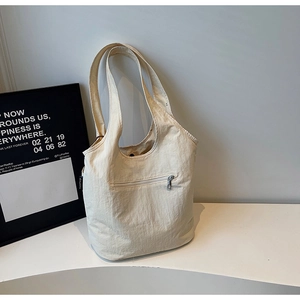 Close-up of lightweight off-white nylon tote bag with metal zipper and front pocket