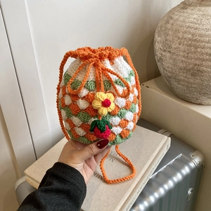 Handmade crochet strawberry bucket bag with colorful knit pattern and floral drawstring