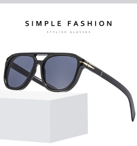 Detail view of black pilot sunglasses featuring stylish golden metal arrow hinge accents