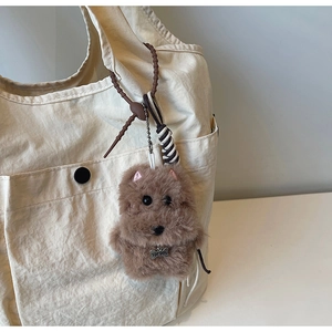 Detail of plush brown dog keychain with TOP DOG silver bone tag on canvas shoulder bag