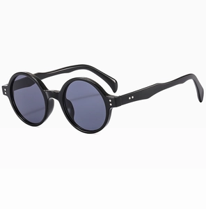 Détail de lunettes de soleil rondes noires rétro avec rivets argentés et branches ondulées