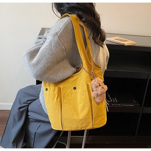 Yellow nylon tote bag with multiple pockets and a brown plush teddy bear charm