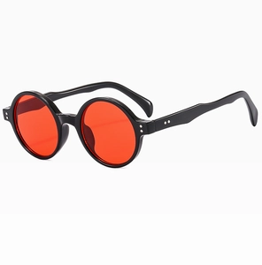 Gros plan de lunettes de soleil rondes rétro avec monture noire et verres rouges vifs