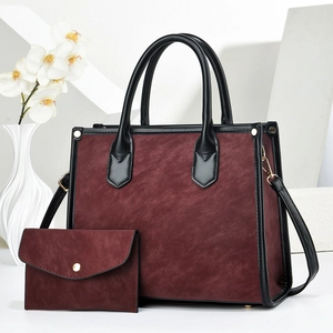 Detail of burgundy textured tote bag set with matching wallet and golden hardware