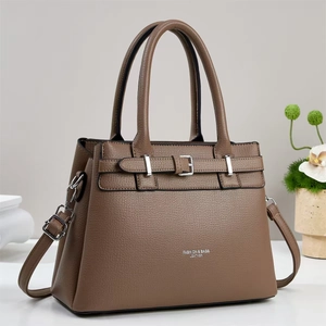 Detail view of brown lychee grain leather handbag with adjustable strap and metal buckle