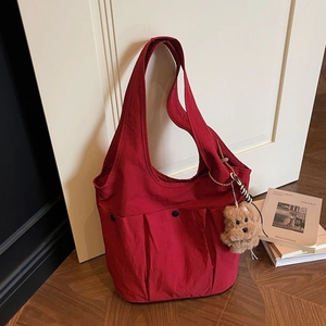 Large red canvas tote bag with multiple pockets and a cute dog charm against a white door