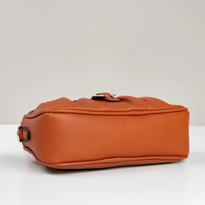 Detailansicht der orangebraunen Ledertasche mit Lychee-Struktur und goldenen Metallhaken