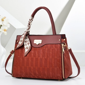 Detail of burgundy shoulder bag with woven texture, golden hardware and silk scarf handle