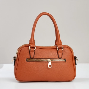 Detail der karamellbraunen Handtasche mit Litschitextur-Leder und goldenen Metallelementen