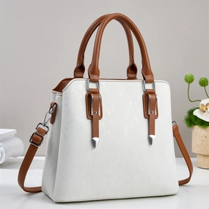 Detailed close-up of a beige and brown shoulder bag featuring elegant silver hardware