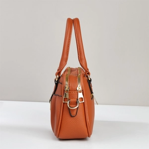 Seitenansicht der braunen Handtasche mit Lychee-Narbenleder und doppelten Goldreißverschlüssen