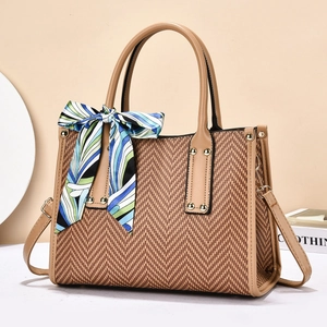 Close-up of V-shaped straw weave bag with leather handles and decorative scarf detail