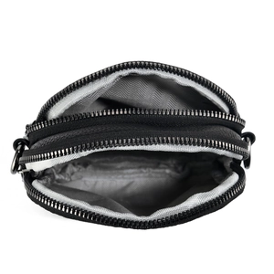 Detailed view of black pebbled leather crossbody bag with triple zipper compartments
