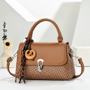 Brown woven crossbody bag for women with unique lock and pendant on minimalist background