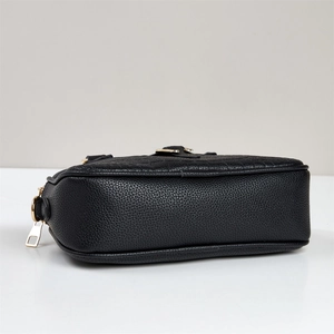 Detail of black pebbled leather texture and gold hardware on the shoulder bag side