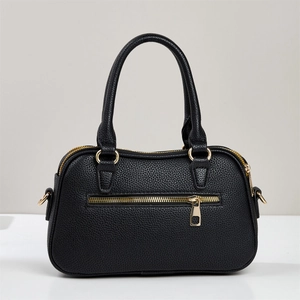 Detail view of black litchi pattern leather tote bag showing golden zipper pocket and d-rings