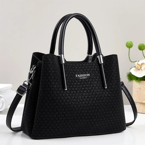 Détail du sac à main noir tressé montrant le logo argenté et la texture du cuir