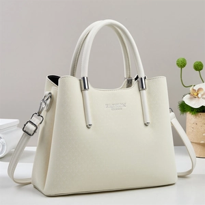 Détail du sac à main blanc cassé avec motif à chevrons et texte Fashion Queen en métal