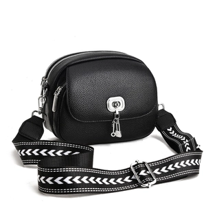 Minimalist black pebbled leather crossbody bag with dual zippers and woven strap