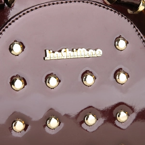 Macro shot of polished burgundy patent leather handbag with gold rivets and logo