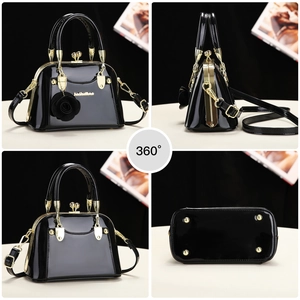 Detail view of mini black patent leather handbag with floral charm and gold base studs