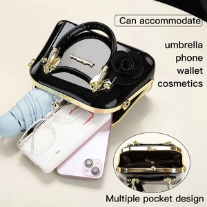 Detail view of black patent leather handbag capacity with gold clasp and rose charm