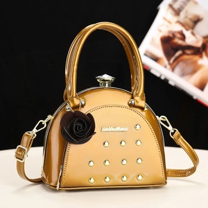 Glossy mustard semi-circle handbag with gold rivets and crystal clasp on a modern stand