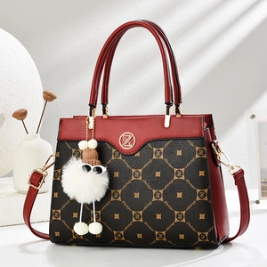 Detail of red and black leather handbag with golden DZ logo and plush monster charm