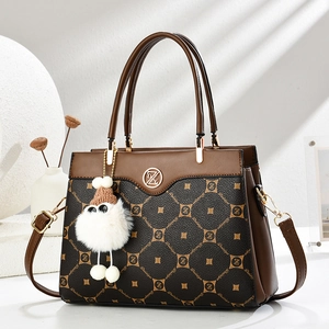 Detail of a dark brown crossbody bag with metal Z logo and white pompom accessory