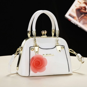 Close-up of white patent leather shell bag with pink rose charm and gold hardware