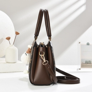 Detailed side view of brown crossbody bag with clover pattern and plush ball charm