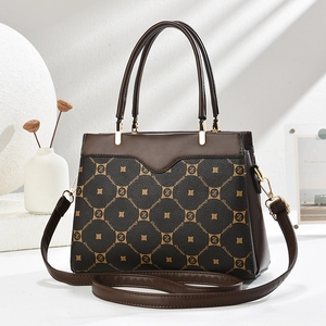 Detail of elegant two-tone brown tote with monogram pattern and gold metal hardware